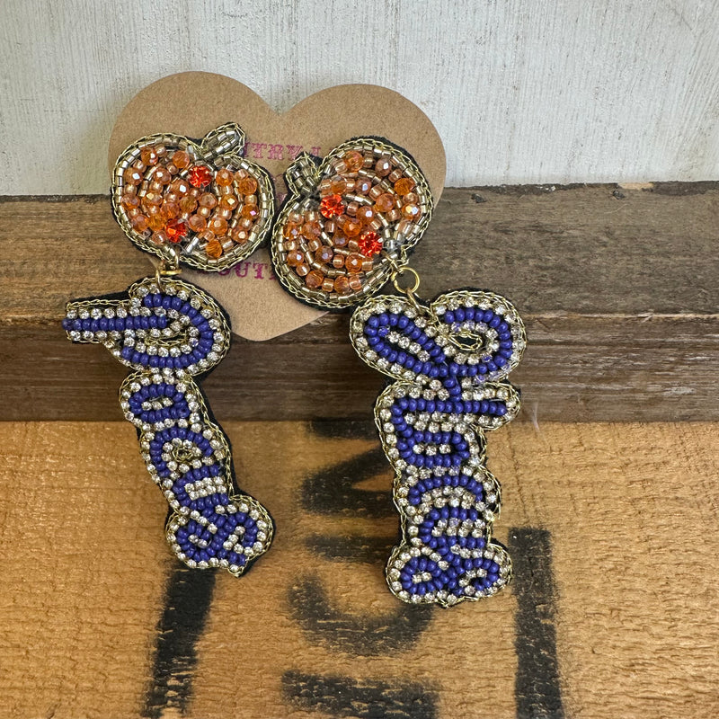 Pair of decorative earrings with blue, orange, and silver design on a wooden surface.