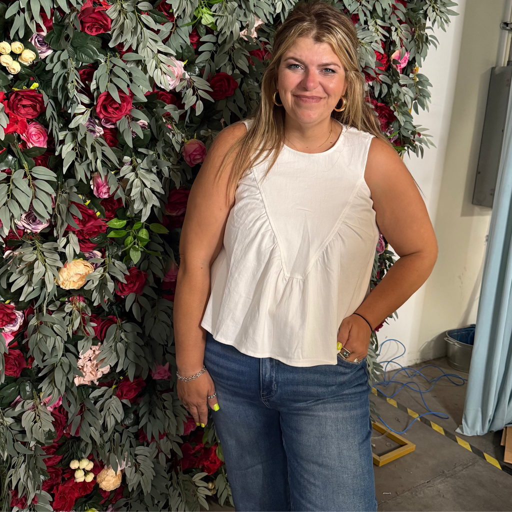 Woman standing in front of a floral wall with a curtain and boxes in the background