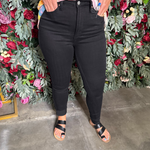 Person wearing black jeans standing in front of a floral wall.