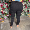 Person wearing black jeans standing in front of a floral wall.