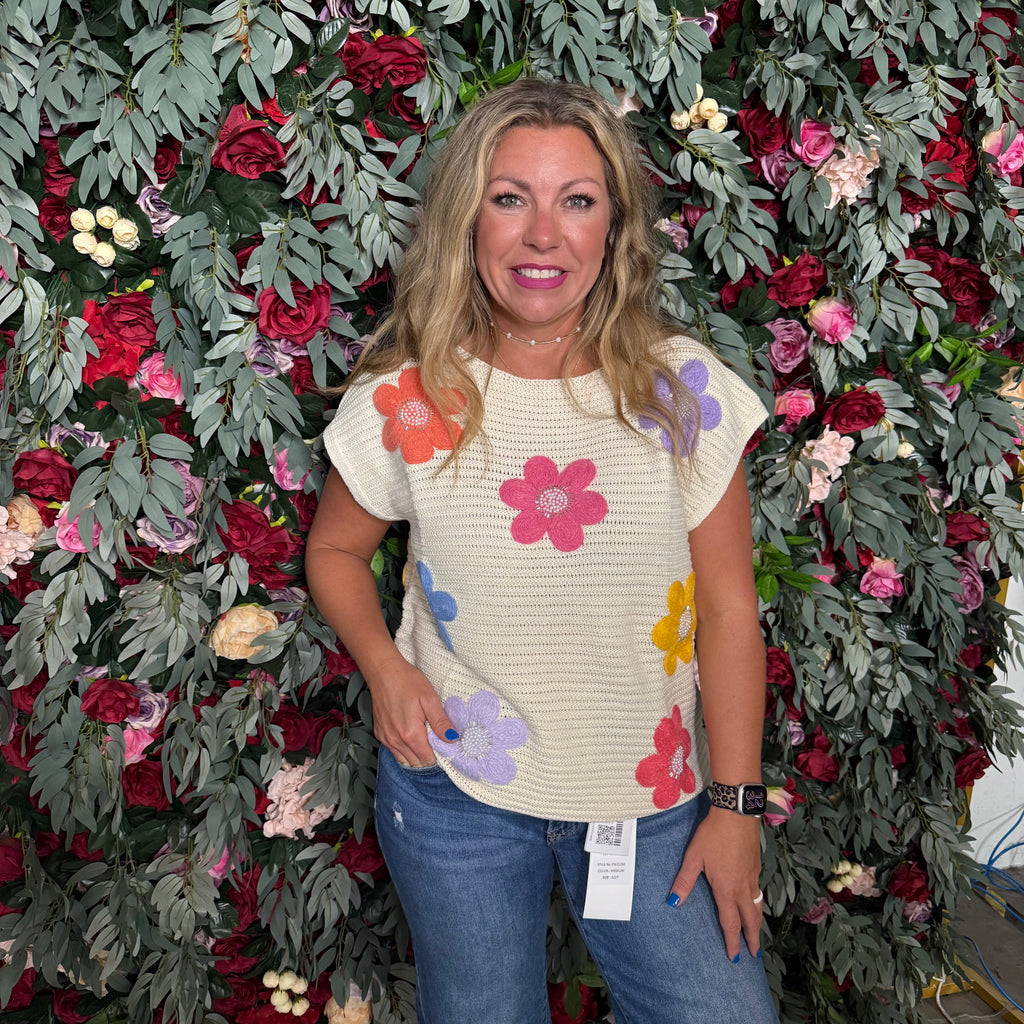 Woman wearing a floral-patterned shirt standing in front of a floral wall