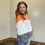 Person wearing a colorful sweater standing in a room with a neutral wall and leopard print rug.