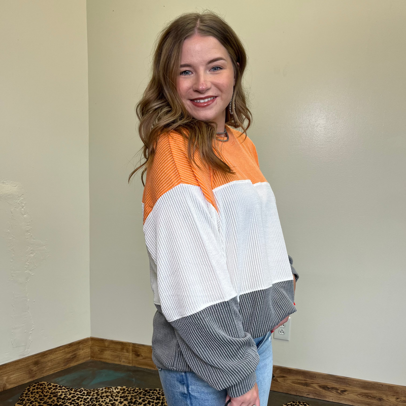 Person wearing a colorful sweater standing in a room with a neutral wall and leopard print rug.