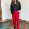 red pants standing in front of a mirror on a leopard print rug.