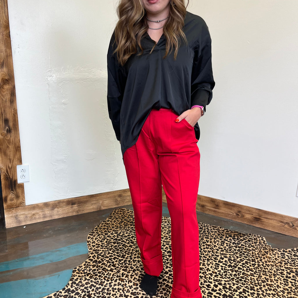 red pants standing in front of a mirror on a leopard print rug.