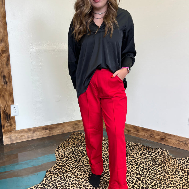 red pants standing in front of a mirror on a leopard print rug.