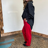 Person wearing a black jacket and red pants standing on a leopard print rug.