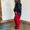 Person wearing a black jacket and red pants standing on a leopard print rug.
