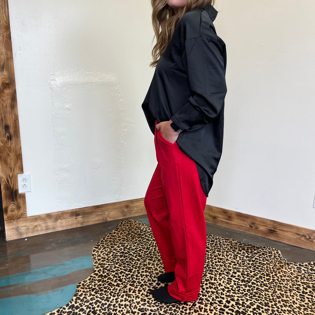 Person wearing a black jacket and red pants standing on a leopard print rug.