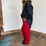 Person wearing a black jacket and red pants standing on a leopard print rug.