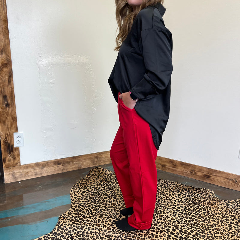 Person wearing a black jacket and red pants standing on a leopard print rug.