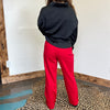 Person wearing a black jacket and red pants standing on a leopard print rug.