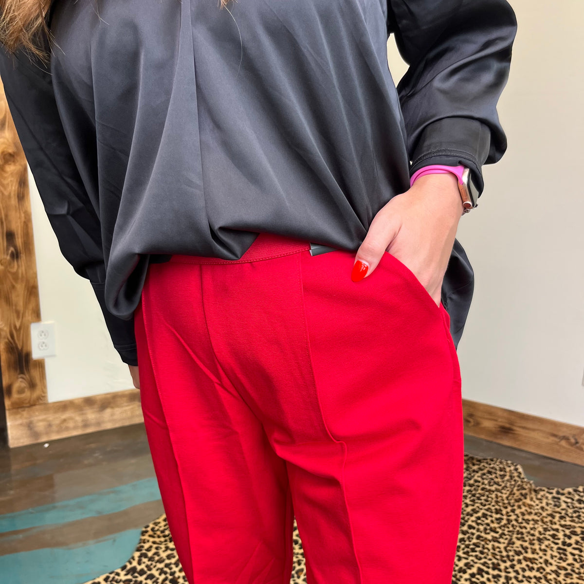 Person wearing a black top and red pants with a neutral background