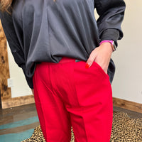 Person wearing a black top and red pants with a neutral background