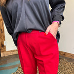 Person wearing a black top and red pants with a neutral background
