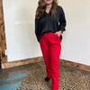 Person wearing a black top and red pants standing on a leopard print rug.