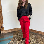 Person wearing a black top and red pants standing on a leopard print rug.