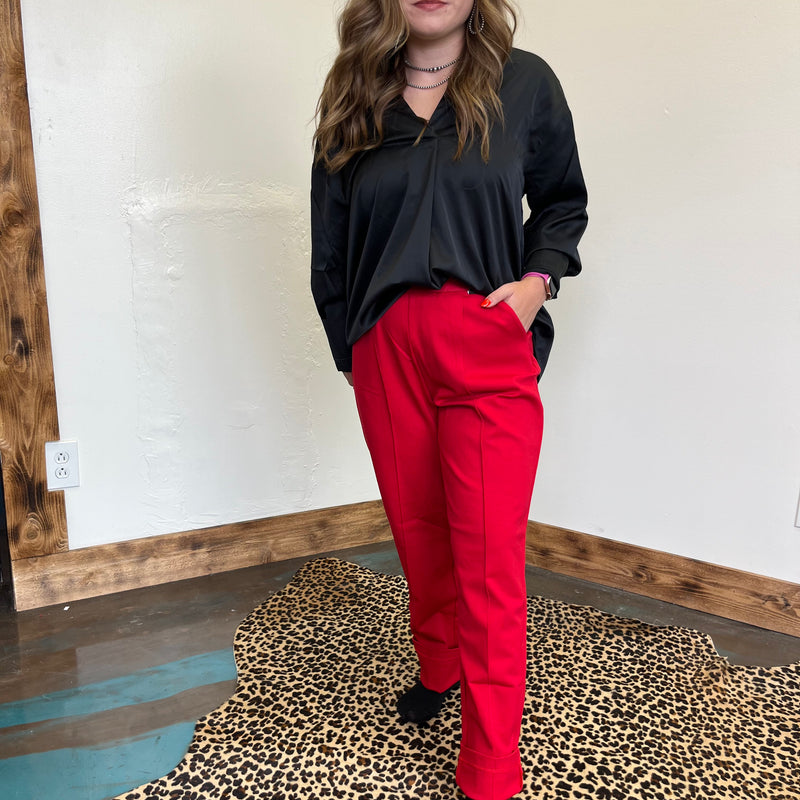 Person wearing a black top and red pants standing on a leopard print rug.