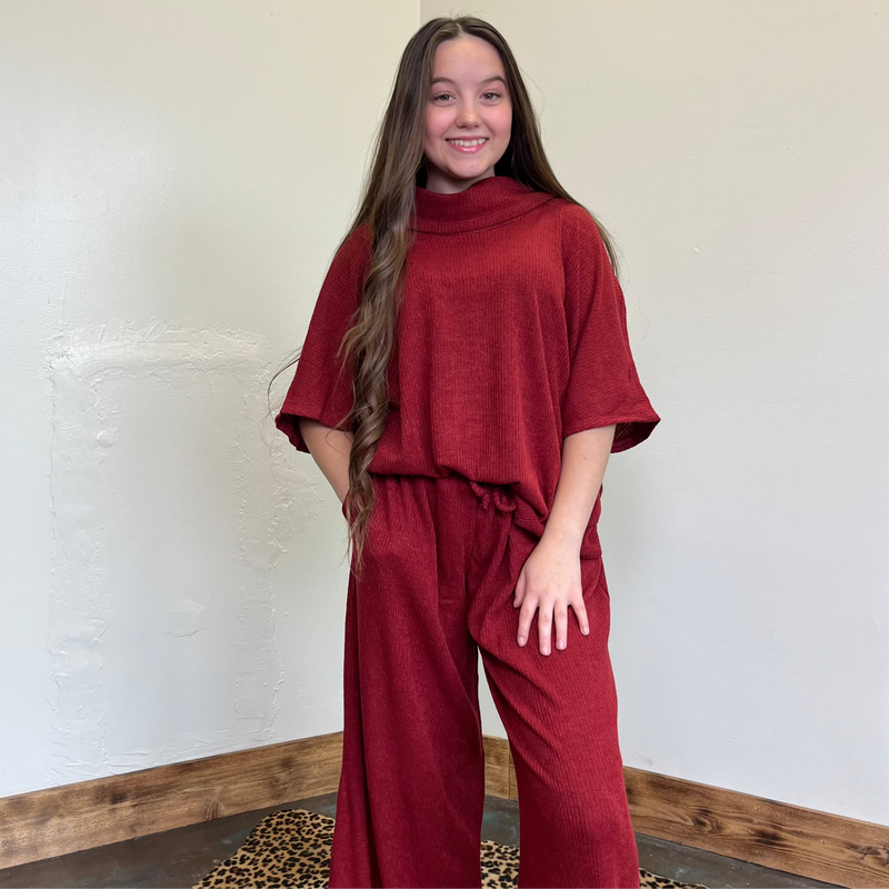 Person wearing a red outfit standing against a white wall.