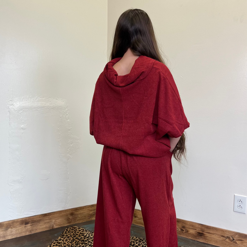 Person wearing a red outfit standing against a white wall.