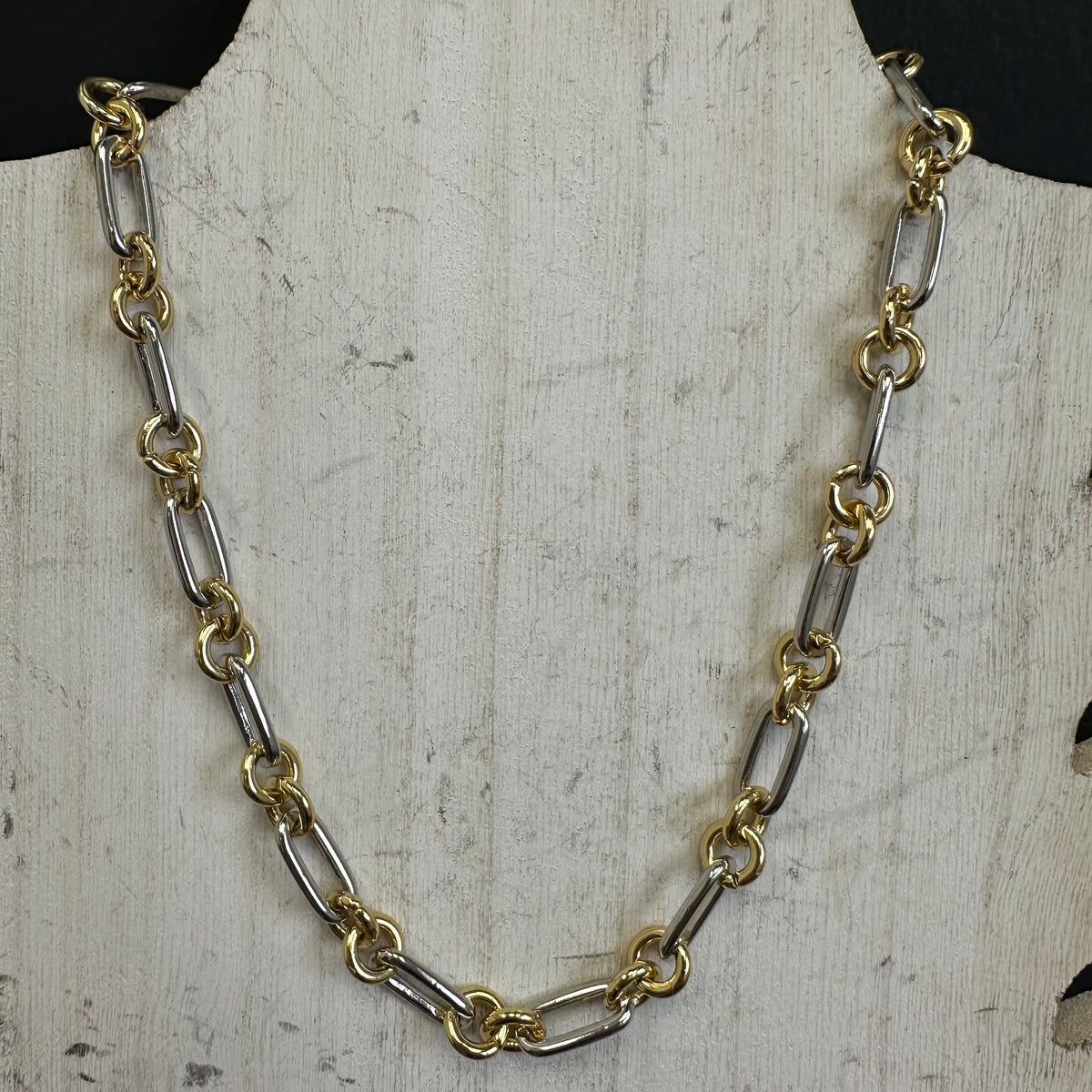 Gold and silver chain necklace on a textured white surface