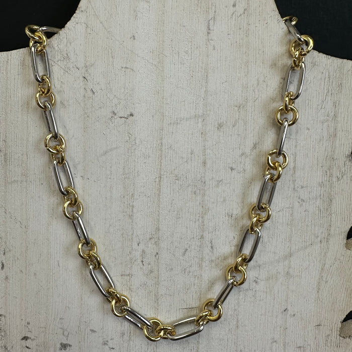 Gold and silver chain necklace on a textured white surface