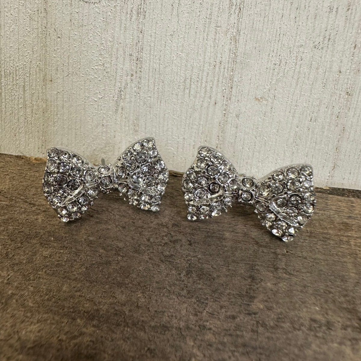 Pair of silver bow-shaped earrings on a textured surface