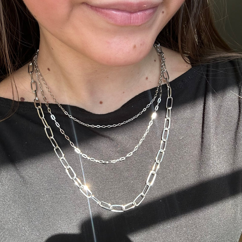 Close-up of a person wearing a silver chain necklace with a blurred background
