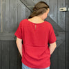 Person wearing a red shirt standing in front of a wooden door