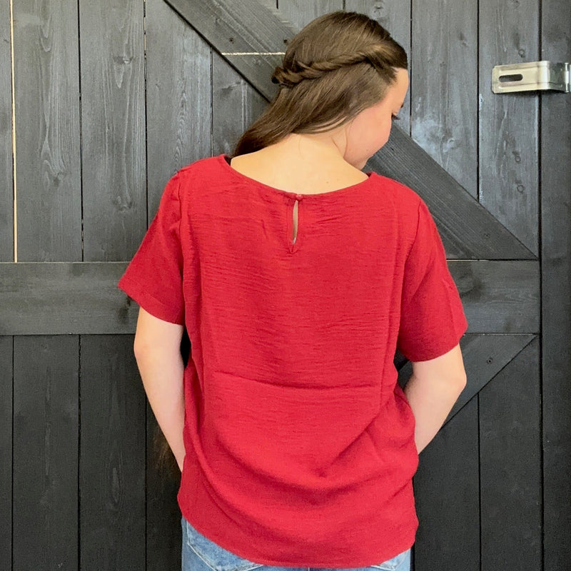 Person wearing a red shirt standing in front of a wooden door