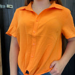 Person wearing an orange short-sleeve shirt against a dark background