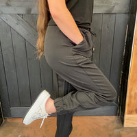 Person wearing a dark green outfit with white sneakers against a wooden background