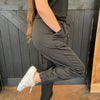 Person wearing a dark green outfit with white sneakers against a wooden background