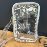 Clear PURSE with gold studs on a wooden surface