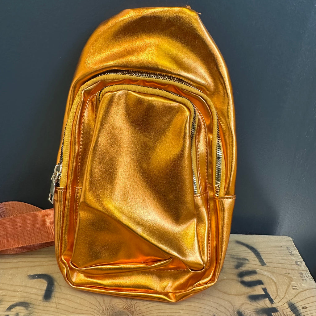 Gold metallic backpack on a textured surface with a dark background