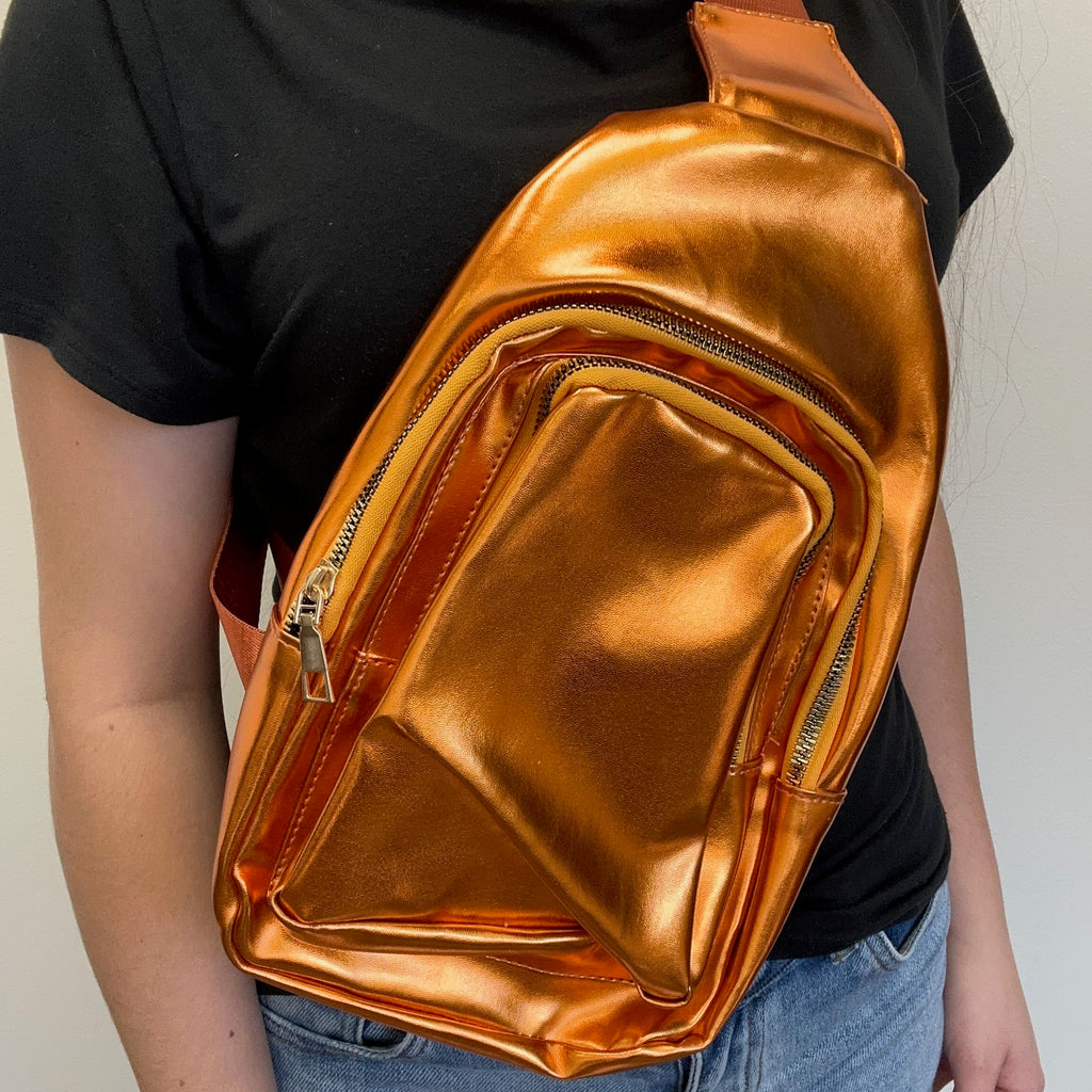 Person wearing a shiny orange waist bag against a neutral background