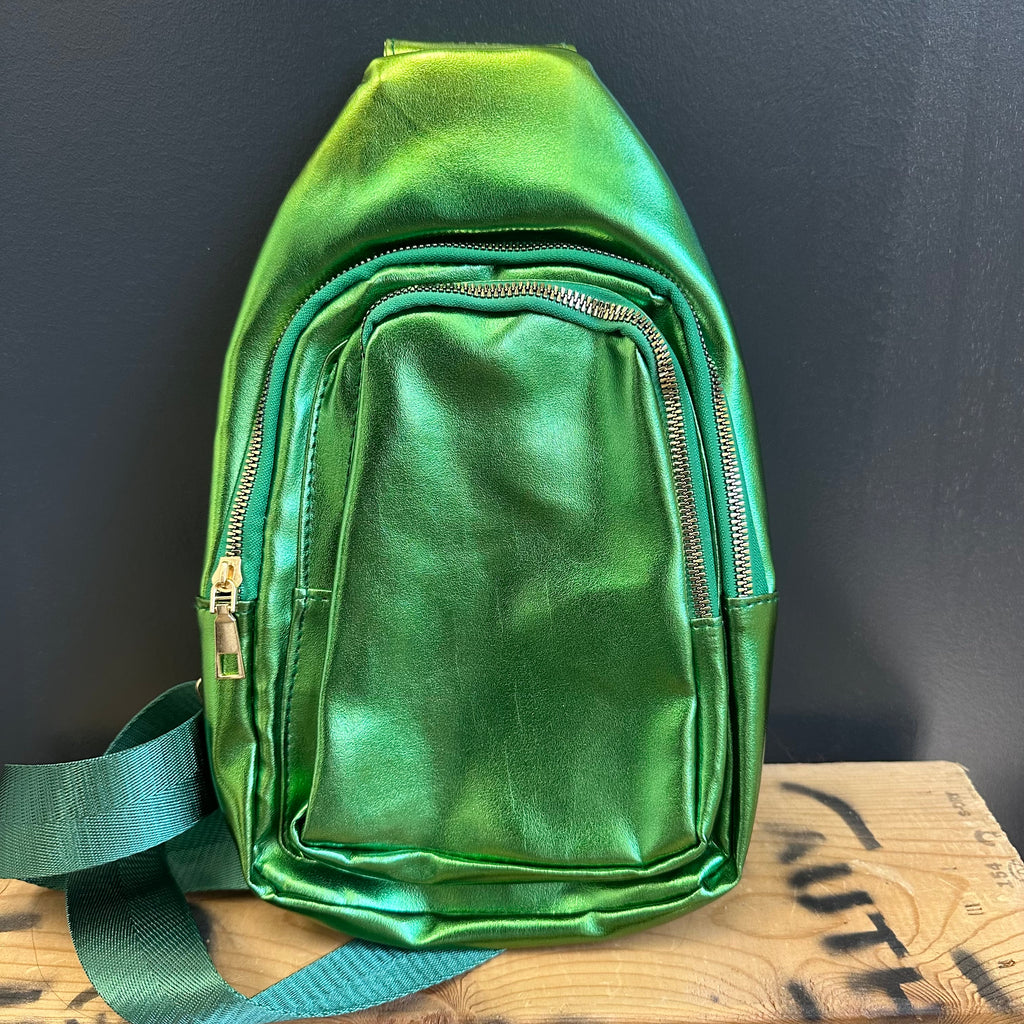 Green metallic sling bag on a wooden surface with a dark background