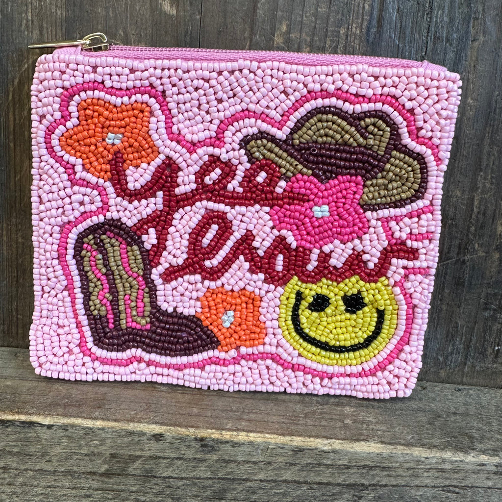 Pink beaded pouch with a smiling mermaid design on a wooden surface
