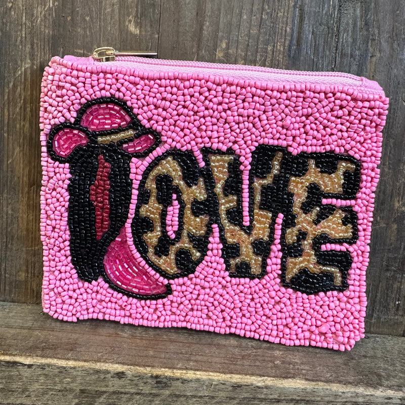 Pink beaded pouch with 'LOVE' in leopard print letters on a wooden surface