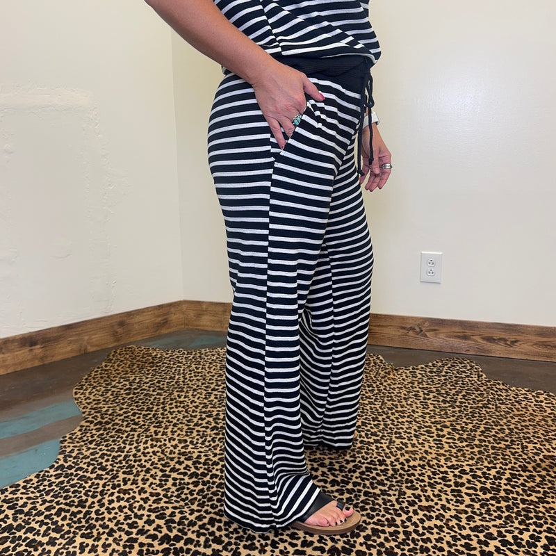 Person wearing black and white striped pants and shirt in a room with a leopard print floor.