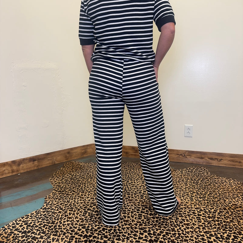 Person wearing a black and white striped outfit on a leopard print floor.