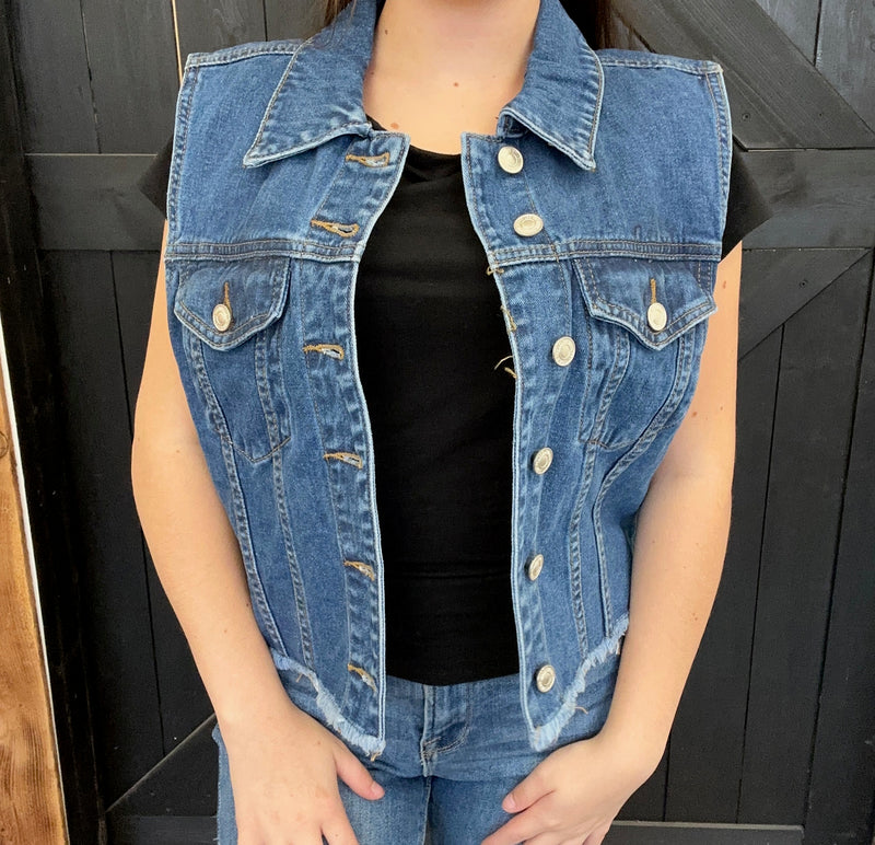 blue denim vest over a black top against a dark background