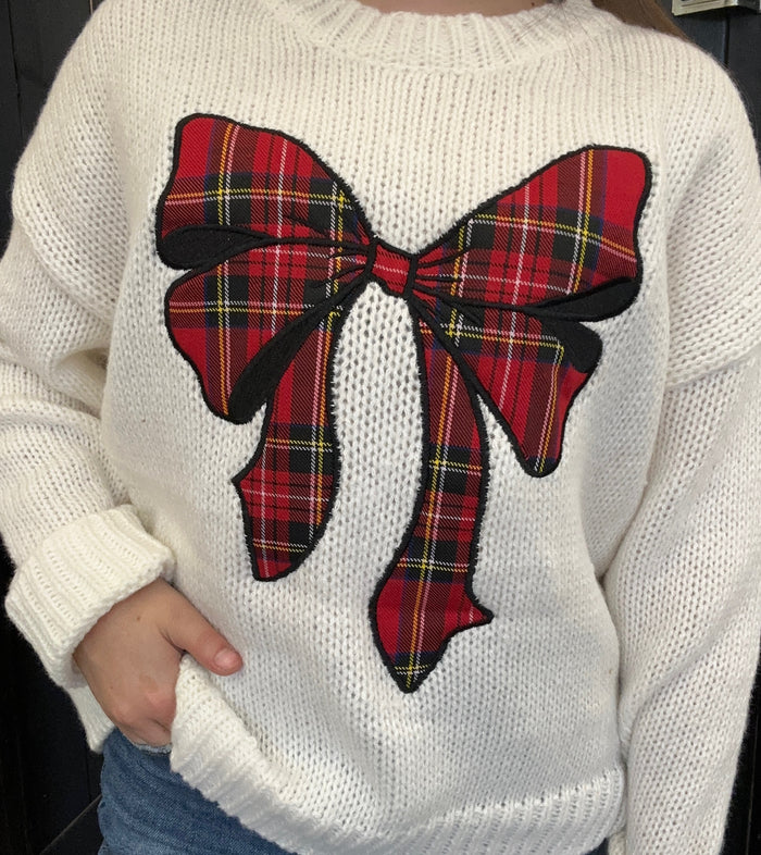 White sweater with a large red plaid bow on the back