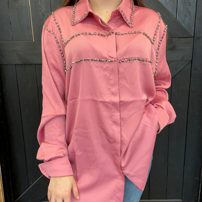 pink shirt with decorative elements against a dark background