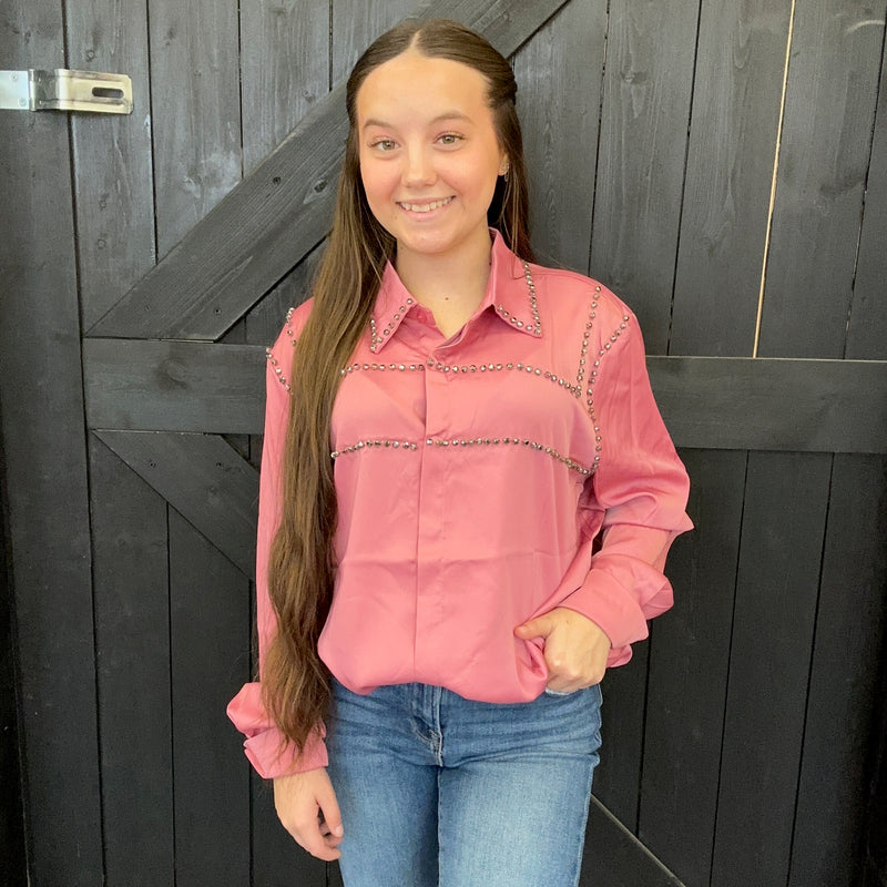 pink shirt with decorative trim against a dark wooden background