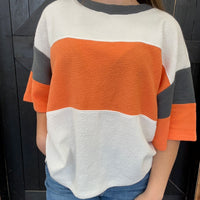 color-blocked sweater with orange, white, and gray sections.