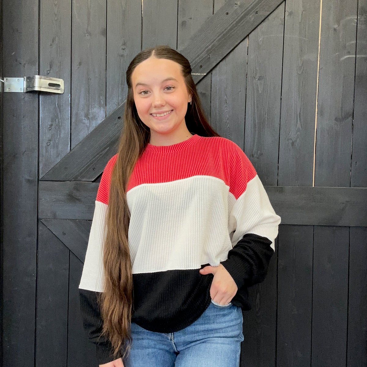sweater standing in front of a wooden door.