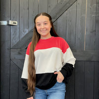 sweater standing in front of a wooden door.