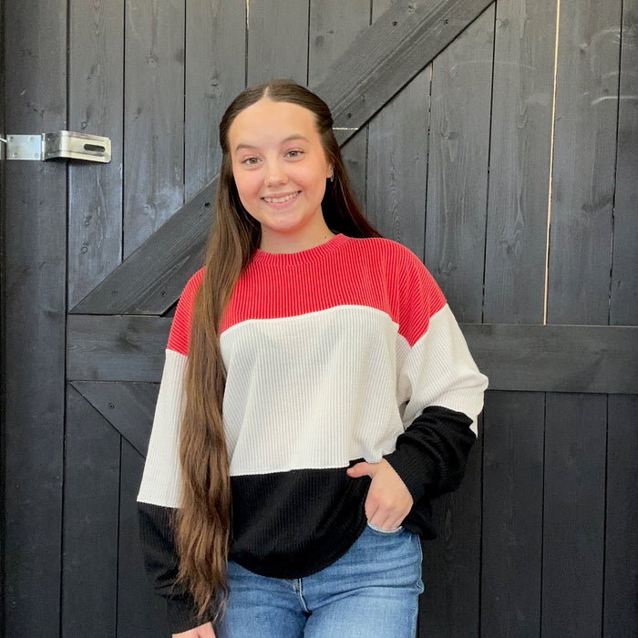 sweater standing in front of a wooden door.