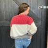 red, white, and gray color-blocked sweater against a wooden background